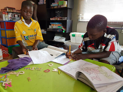 Boys writing in exercise books at desks in a classroom